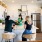 Friends gathered around a modern kitchen island with white cabinets, stainless steel appliances, and bright decor, enjoying a casual moment together