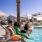 Group of friends relaxing by the pool, dipping their feet in the water and enjoying a sunny day at Canopy community